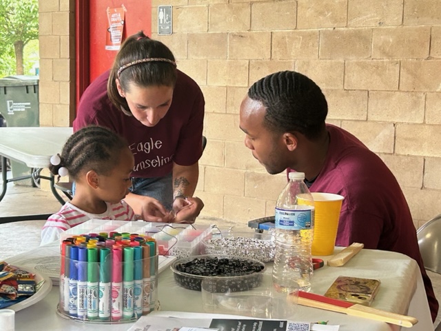 Two NCCU students with young visitor engaged in activity